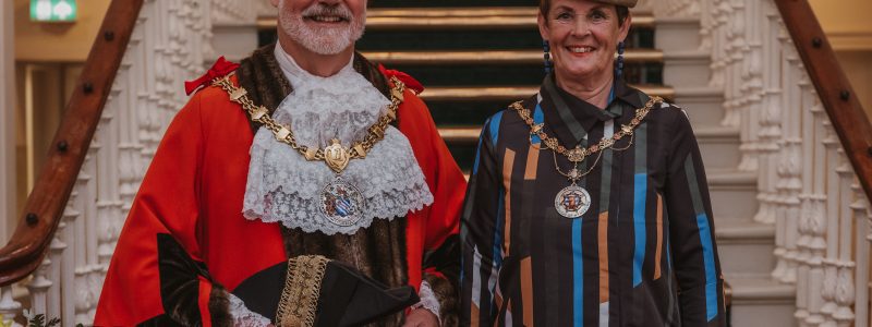 Mayor and Mayoress in formal dress and mayoral chains at Accrington Town Hall. Staircase in background
