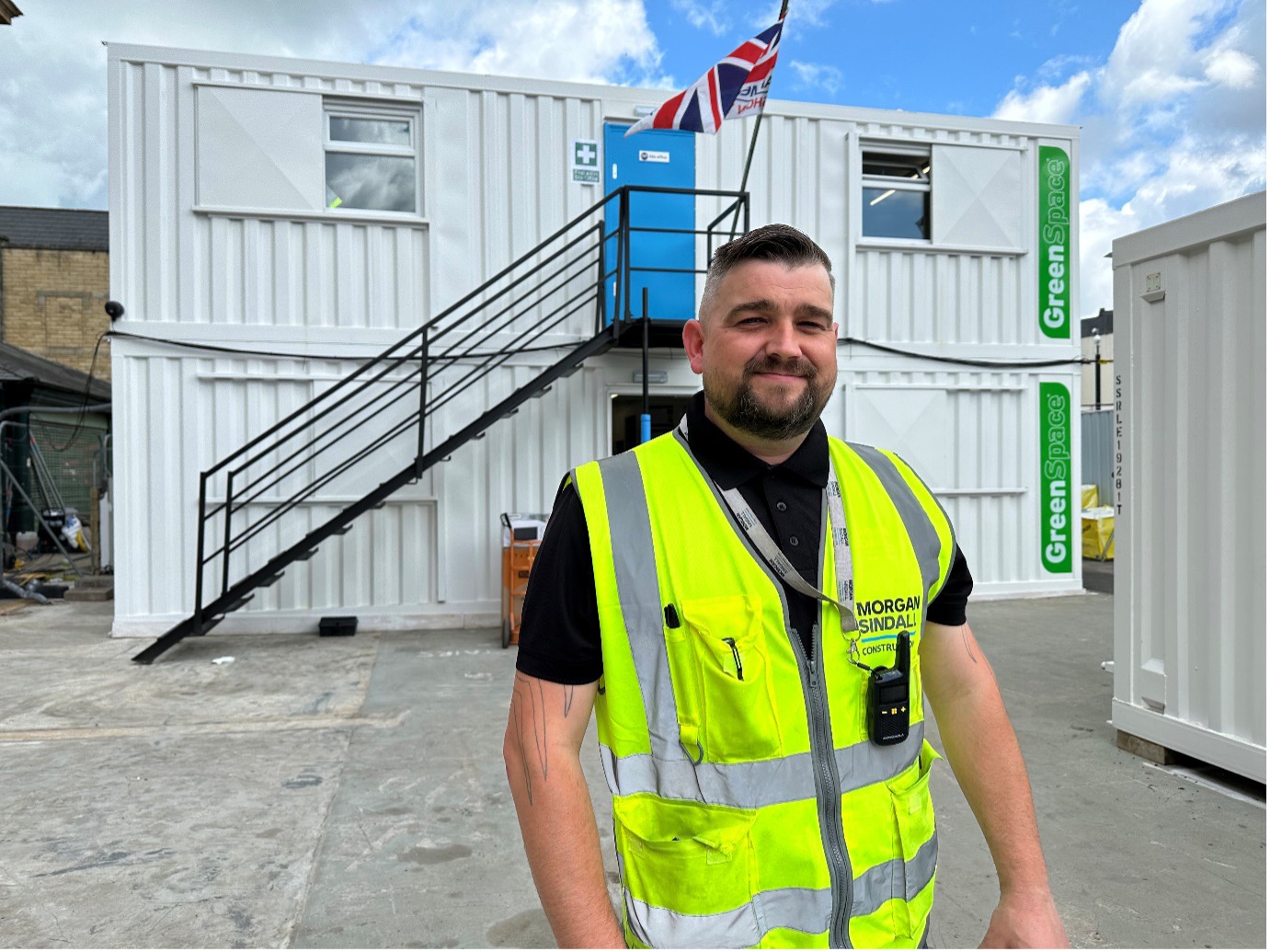 Roy Duckworth in black shirt and hi vis vest. Shipping containers in background