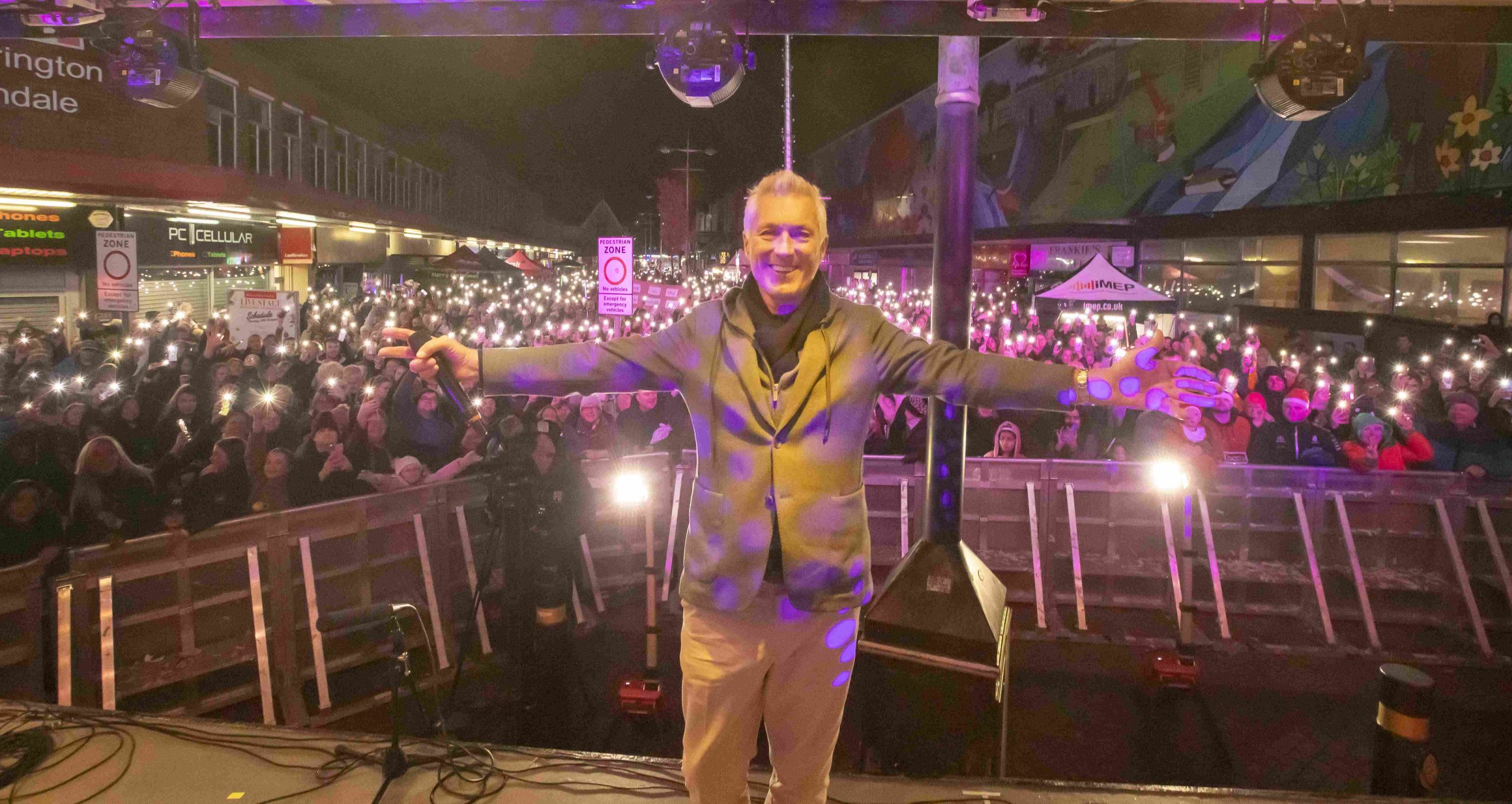 Martin Kemp with crowds in background shining lights on their mobile phones