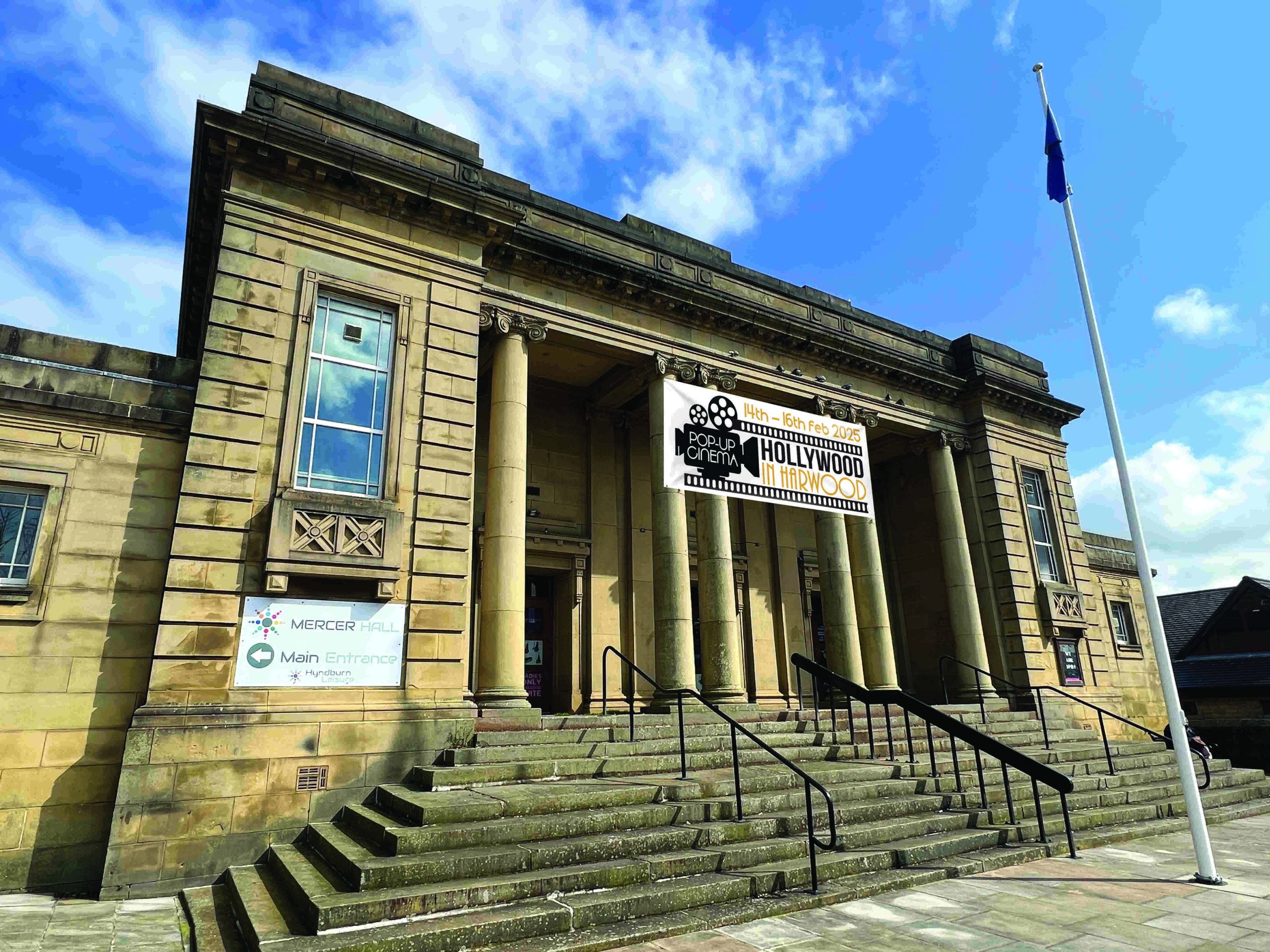 Large building with stone steps and pillars. Blue skies above.