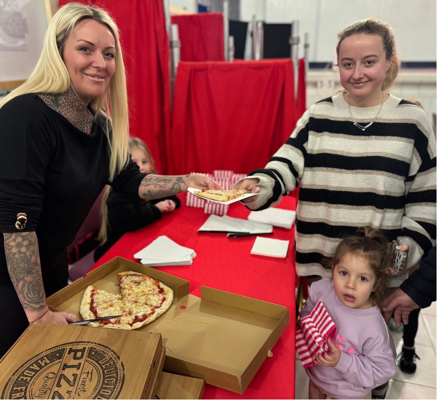Person handing pizza to mother and child