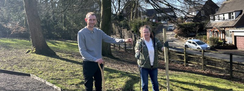 Two people alongside hole dug to plant new tree