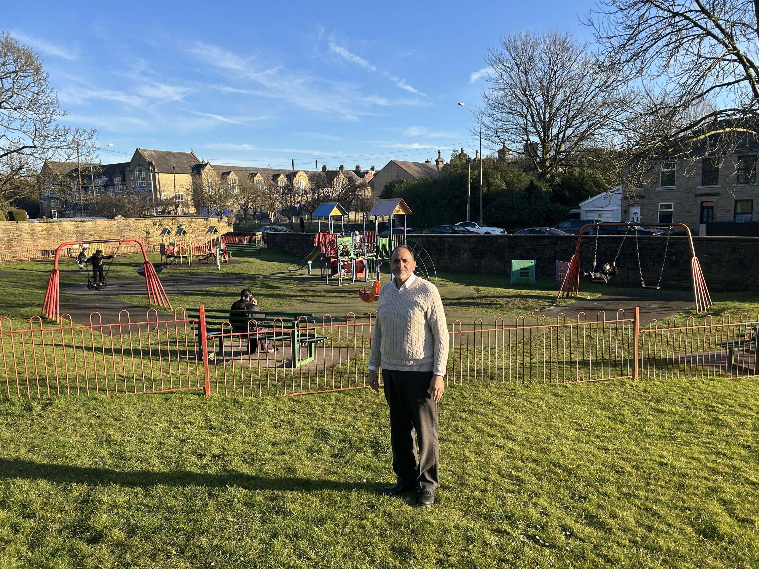 A person standing in a park with play area in background