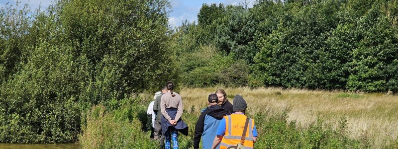 A group of people walking along a footpath next to some water.