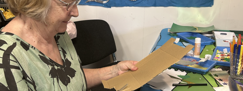 Lady cutting cardboard while crafting