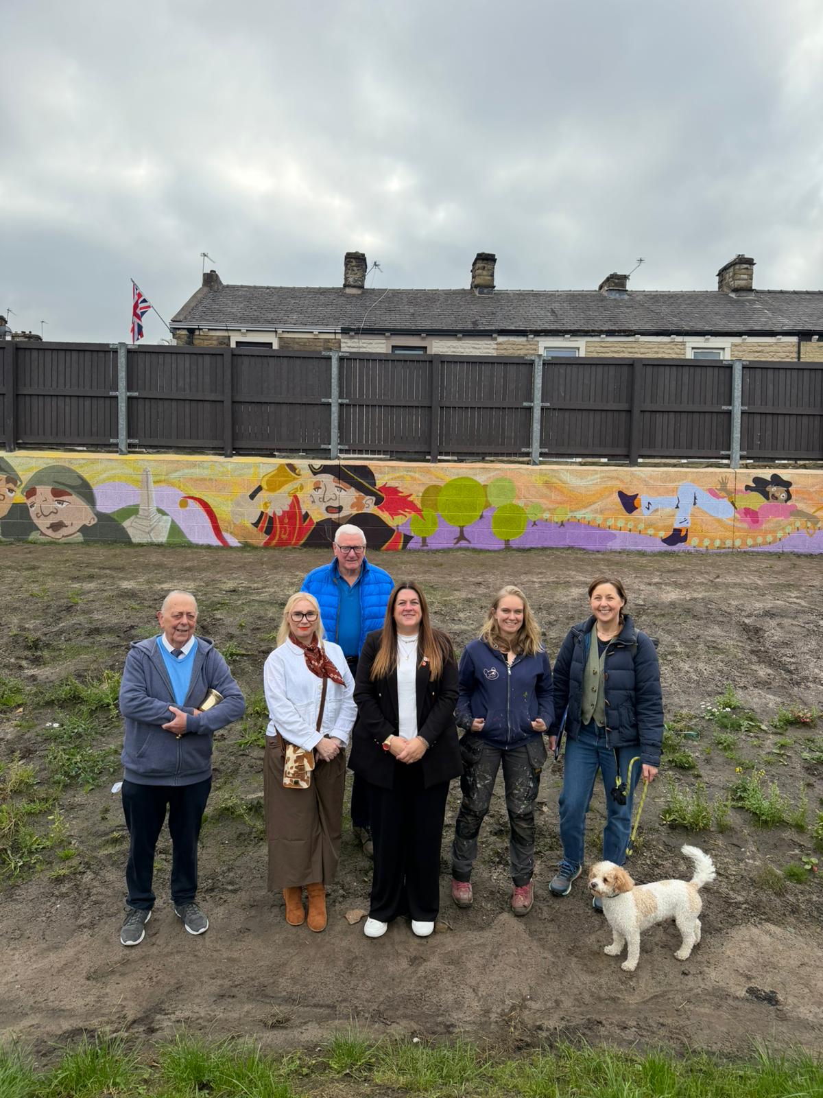 People and dog in front of art mural