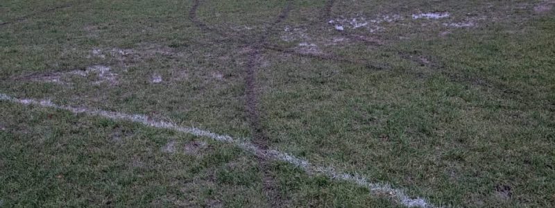 a football pitch with tracks caused by a motorbike