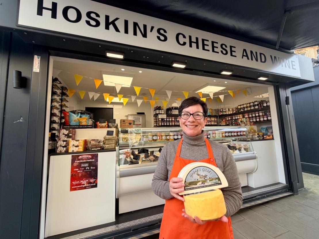 person holding cheese outside a cheese stall
