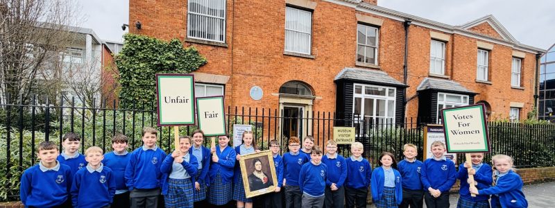 School children holding banners outside museum
