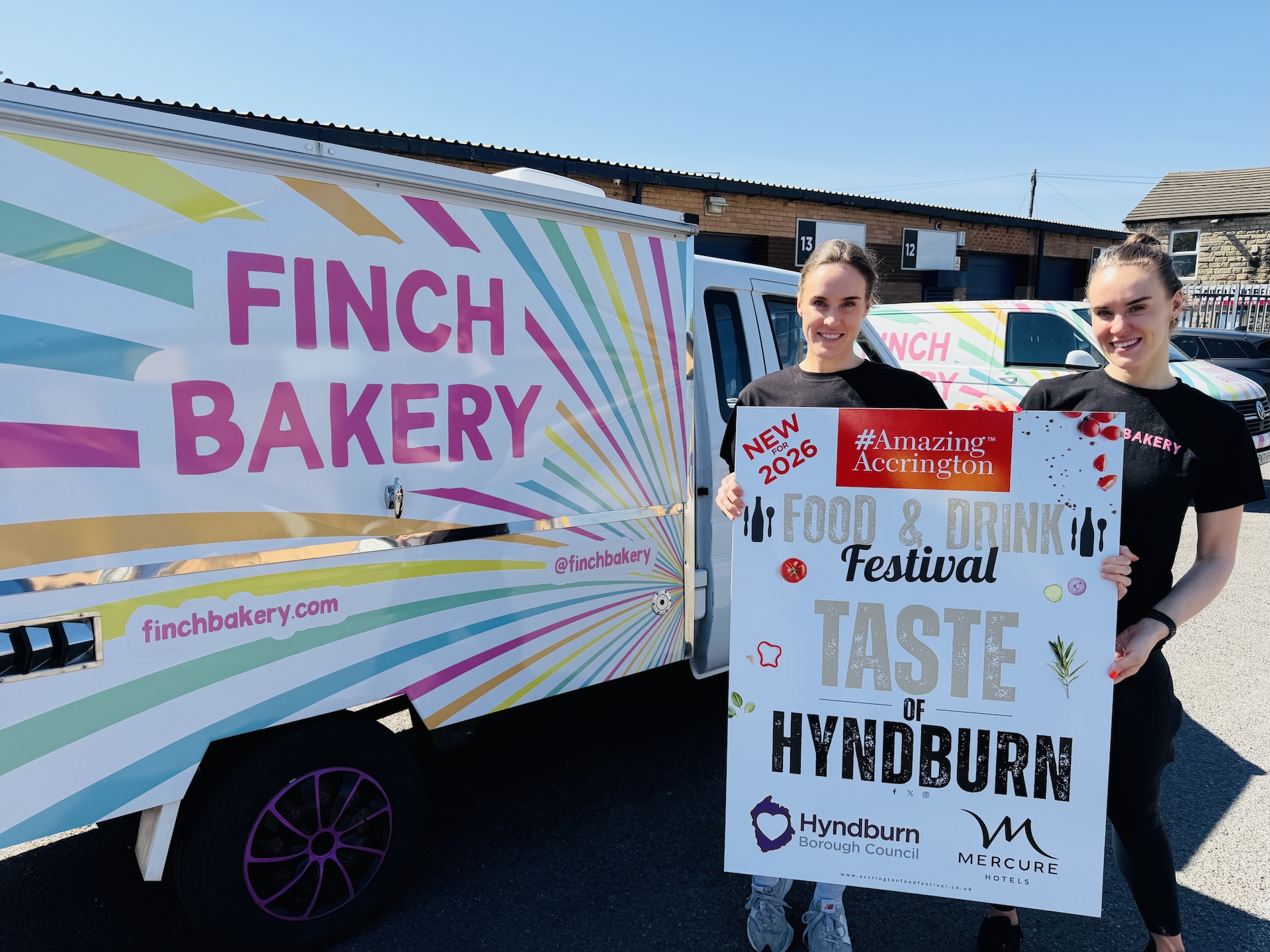Two people holding a sign which says Taste of Hyndburn