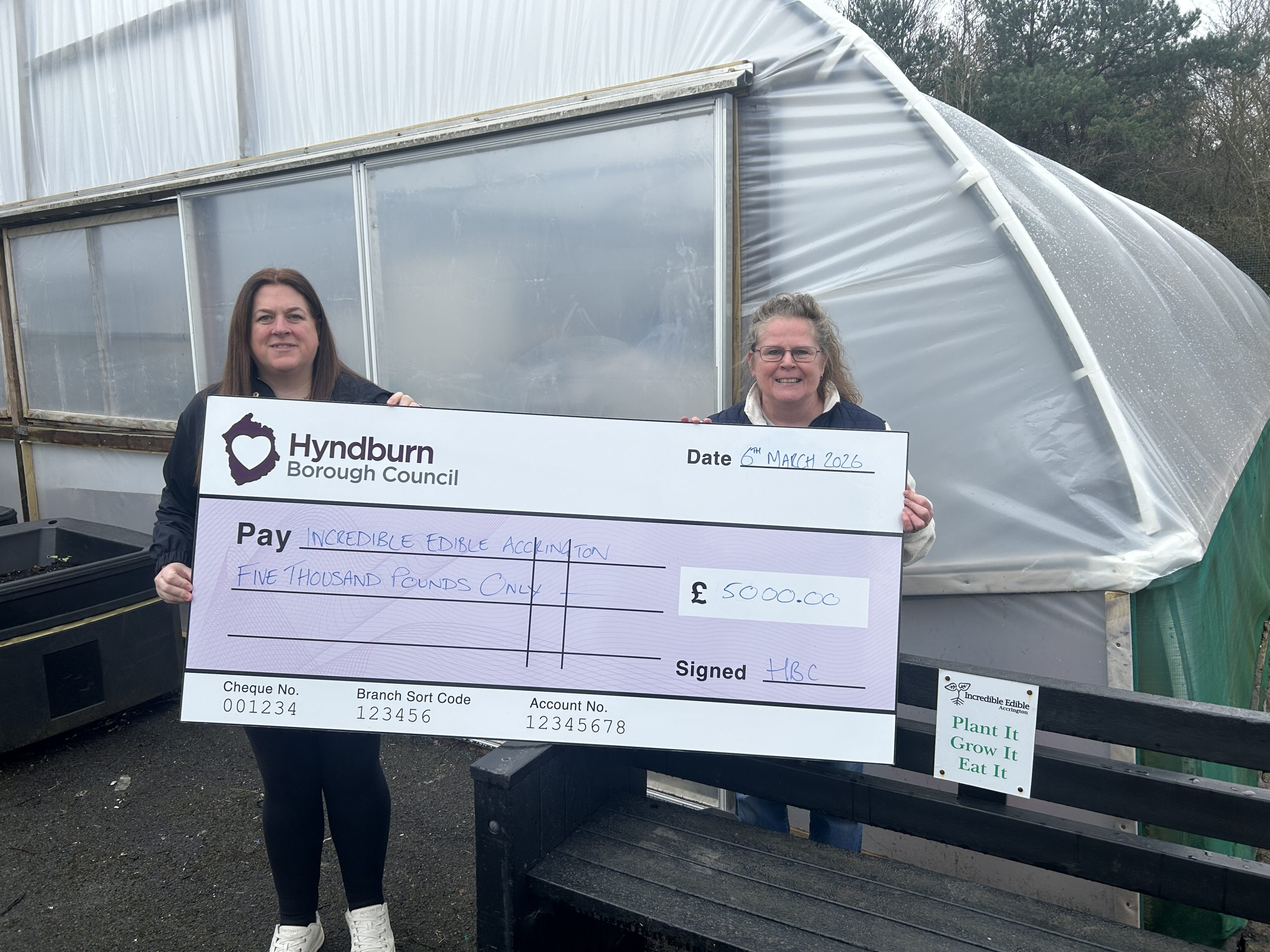 Two people holding giant cheque