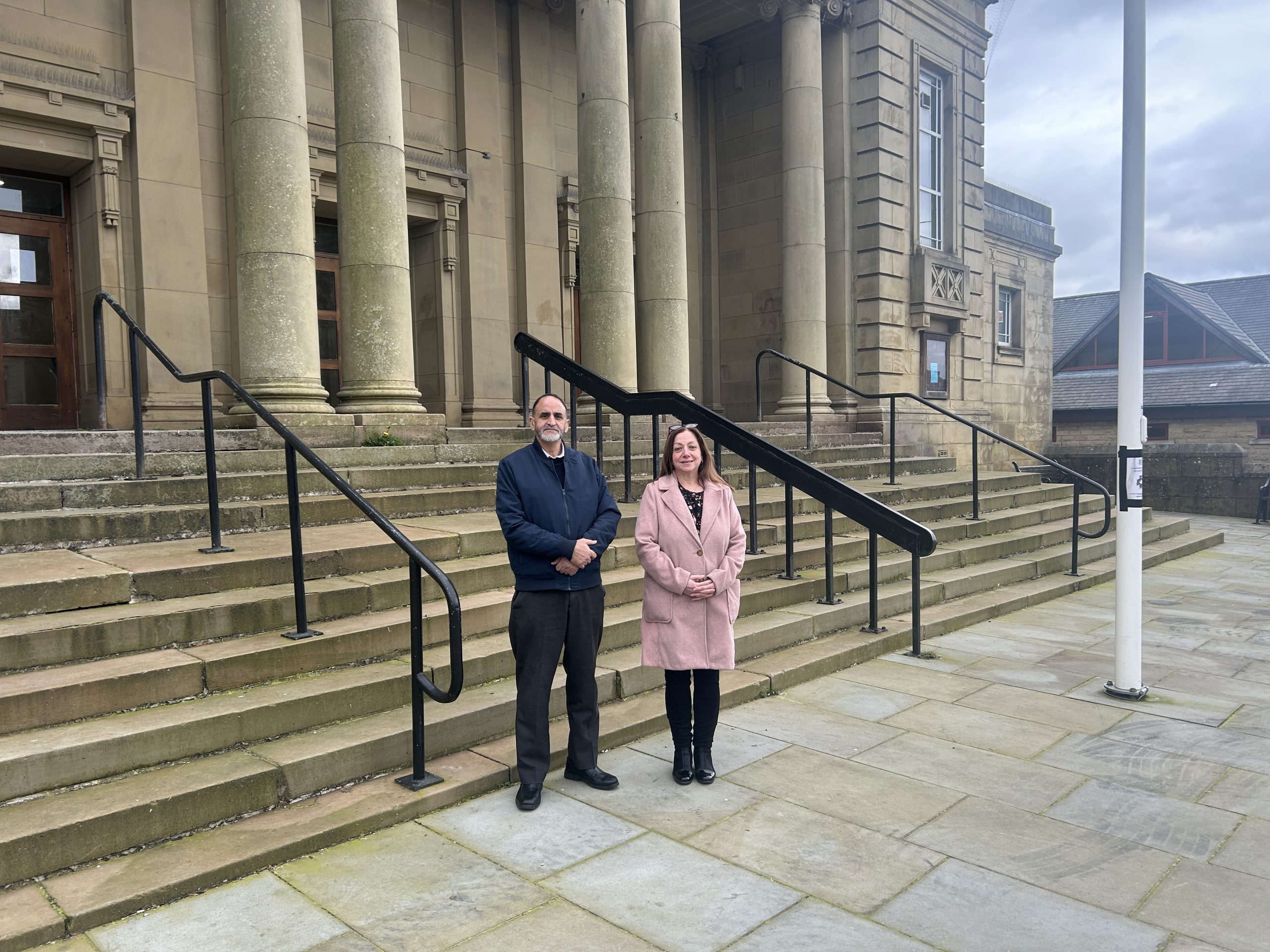 Two people outside large building with stone pillars and steps