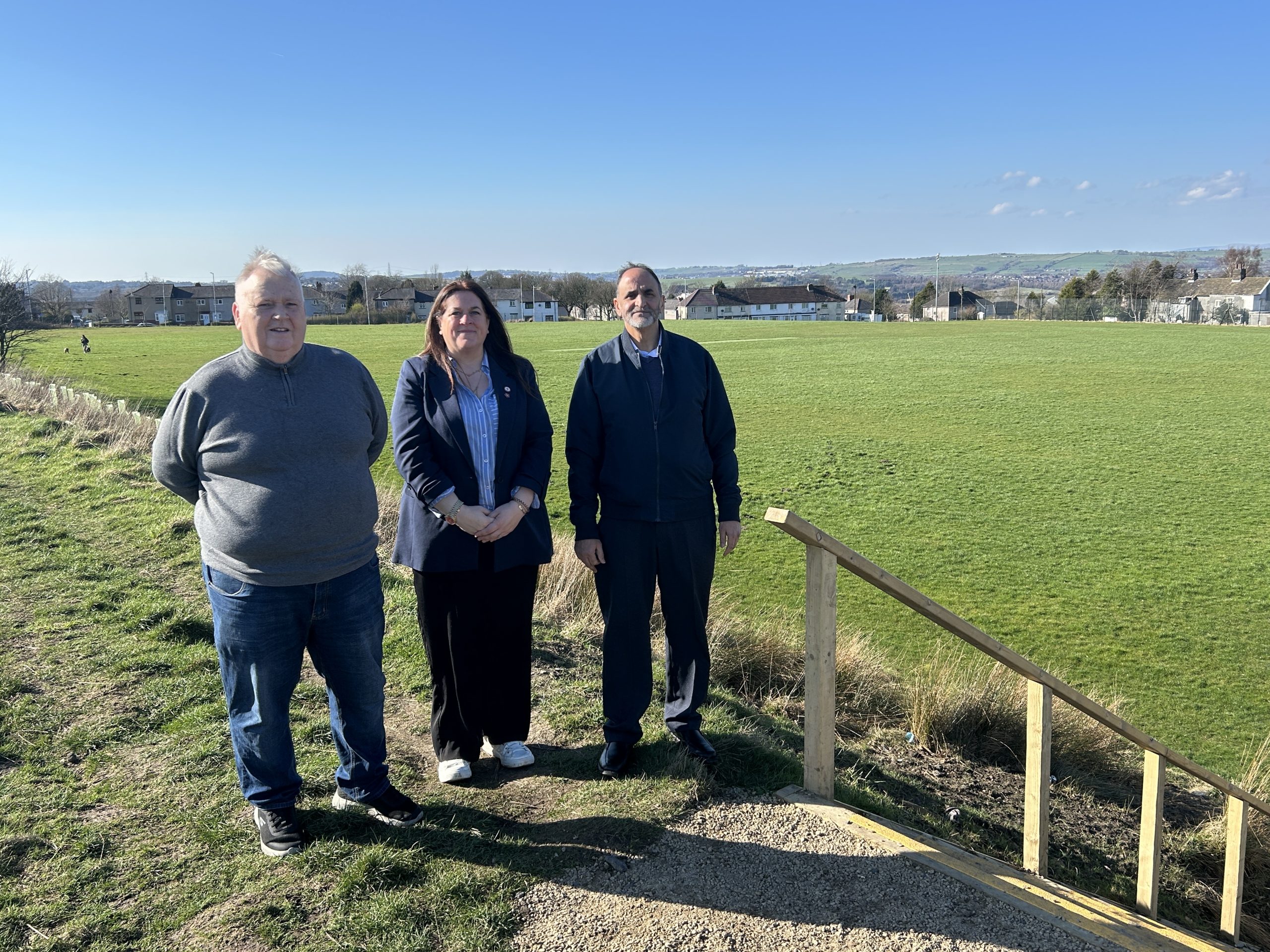 Three people in an open green space