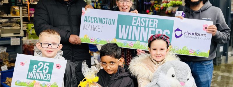 Adults and children holding an Easter winner sign and prizes.