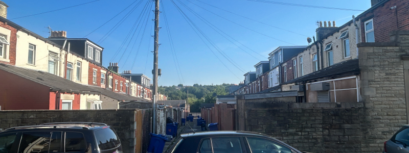 Two cars parked blocking a back alley