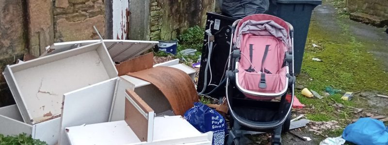 Piles of rubbish which have been fly-tipped on a back alley