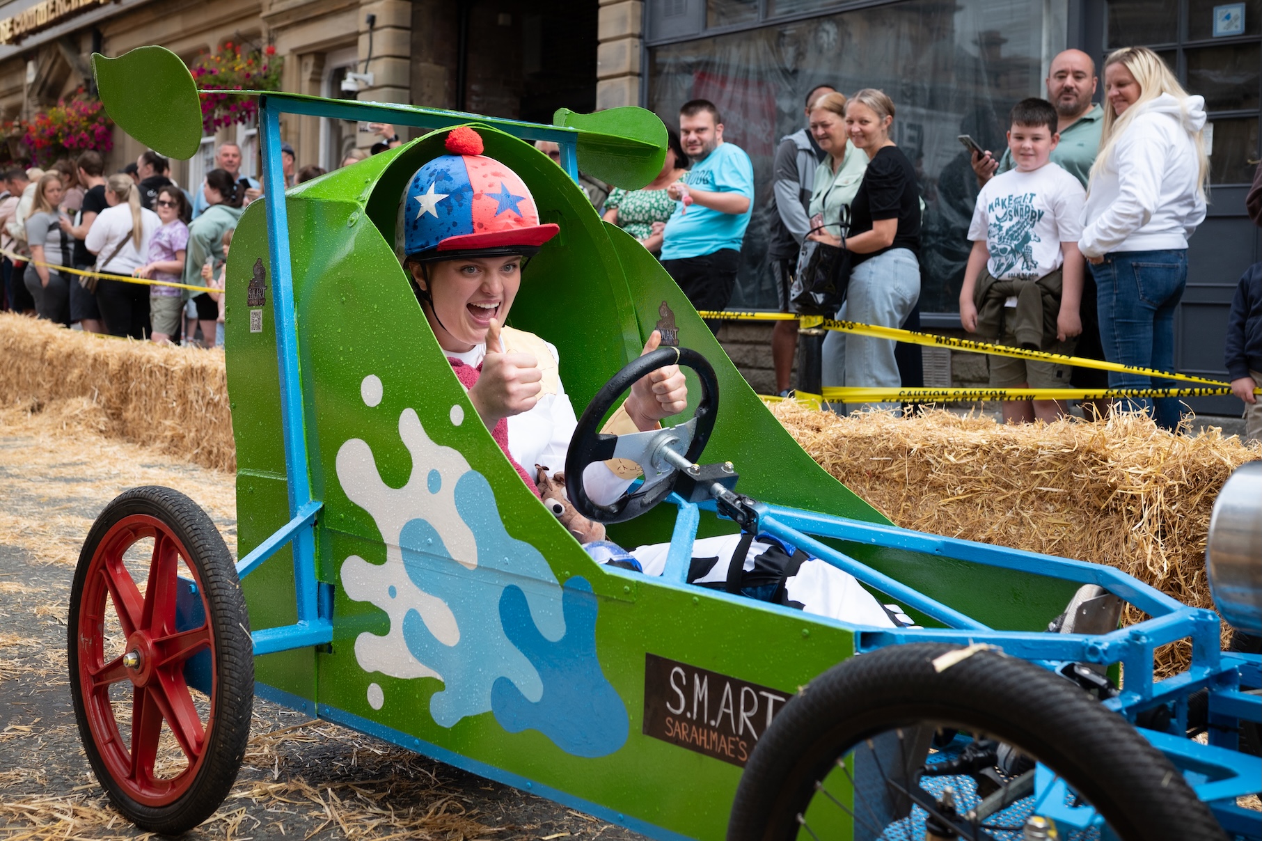 A person driving a soapbox cart as spectators watch