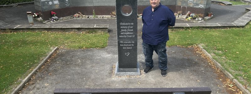 Person standing next to a memorial at the cemetery