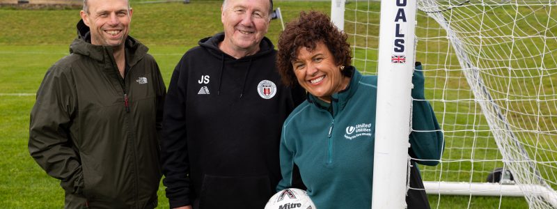 Three people stood by a football goal